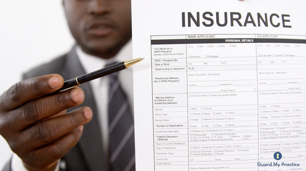 A physician holding a pen pointing at an insurance application form.
